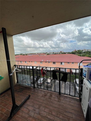 View from a balcony overlooking parking area and residential buildings.