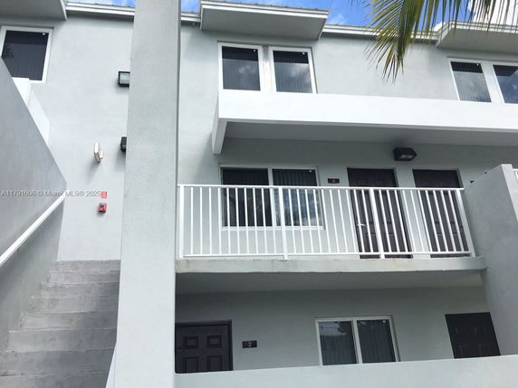 Front view of a two-story residential building with balconies and stairs.