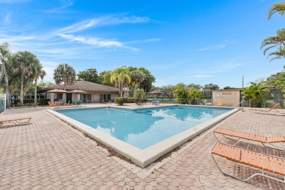 Outdoor swimming pool area with loungers and surrounding greenery.