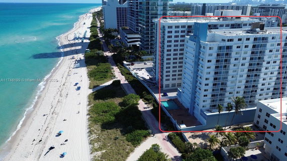 View of tall beachfront buildings with a sandy beach and ocean adjacent.