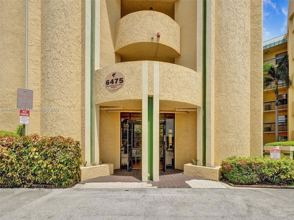 Front view of a multi-story building entrance with a circular design and signage displaying the number 6475.