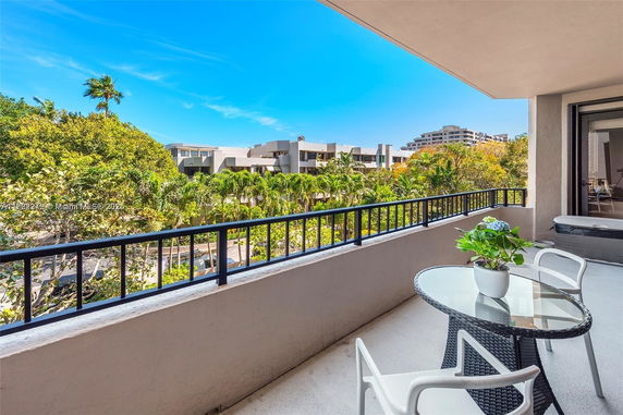 Balcony view overlooking a lush green area with buildings in the background.