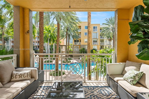 View from a balcony overlooking a swimming pool and palm trees.