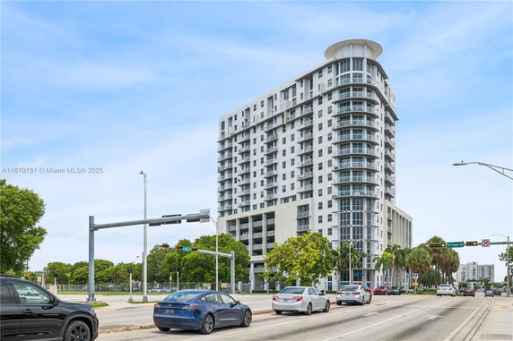 Front view of a modern multi-story building with balconies and large windows.
