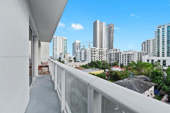 View from a balcony showing surrounding tall buildings and green areas.