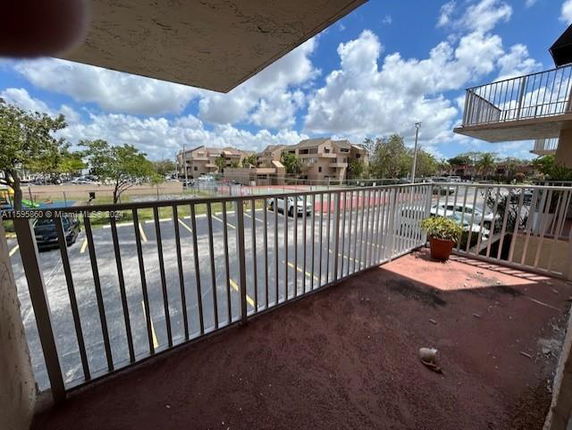 View from a balcony overlooking a parking lot and nearby buildings.