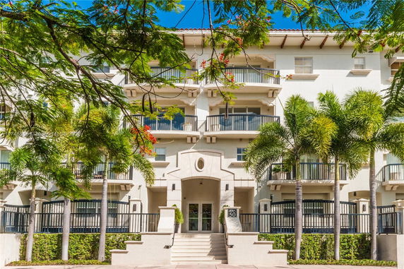 Front view of a multi-story building with balconies and palm trees.