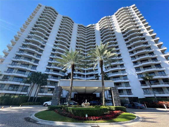 Front view of a tall residential building with multiple balconies.