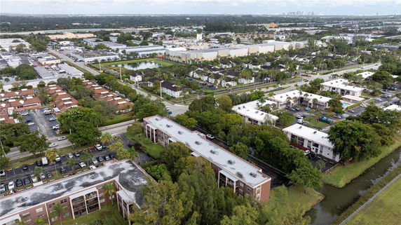 Aerial view of a suburban area with multiple residential buildings, roads, and green spaces.