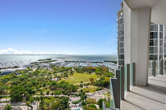Panoramic view of a coastal area with boats and greenery seen from a high-rise building.