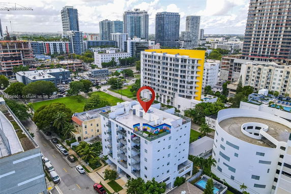 Aerial view of a cityscape with multiple modern buildings and a white building with a rooftop garden.
