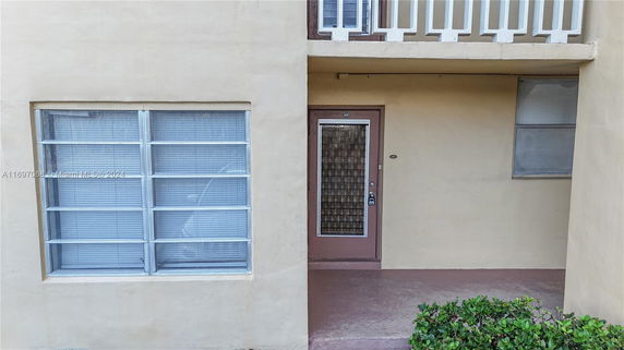 Front view of an apartment entrance with beige walls and windows.