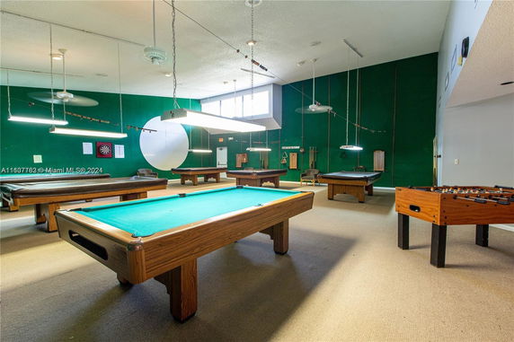 Room with multiple billiard tables and a foosball table.