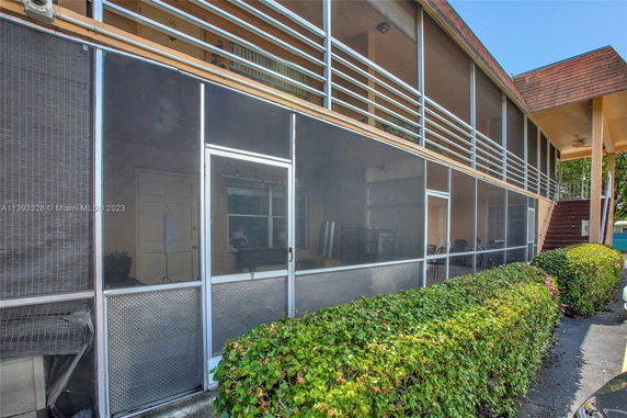 Front view of a two-story building with screened porches and stairway entrance.