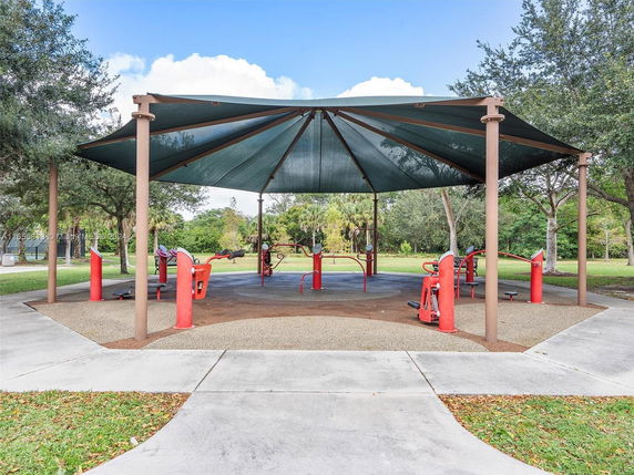 Covered outdoor exercise area with red fitness equipment.