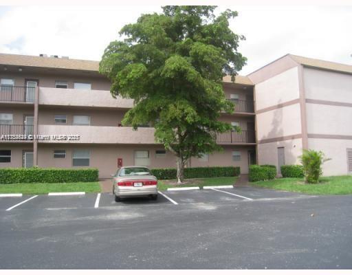 Front view of a three-story residential building with a parking area.