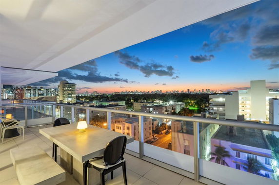 A balcony view at sunset showcasing a city skyline and surrounding buildings.