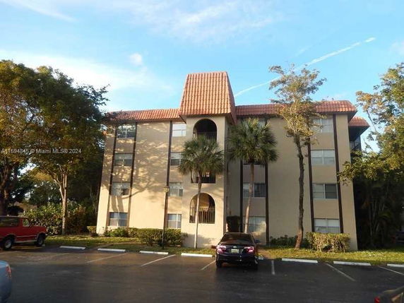 Front view of a multi-story apartment building with a tiled roof and arched balcony openings.