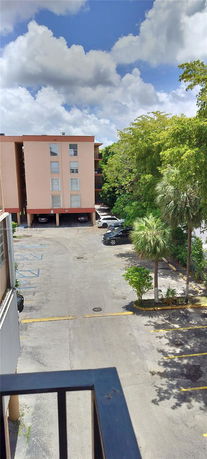 View of a multi-story building and parking area surrounded by trees.