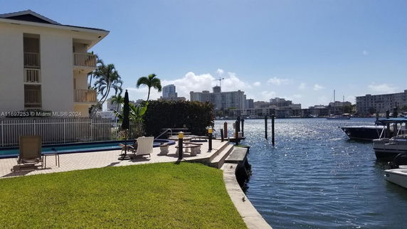 Outdoor swimming pool area with lounge chairs next to a waterfront.