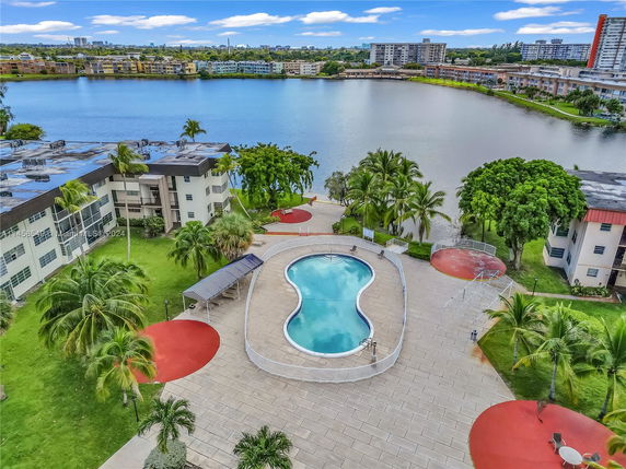 View overlooking a pool area with adjacent multi-story residential buildings by a water body.