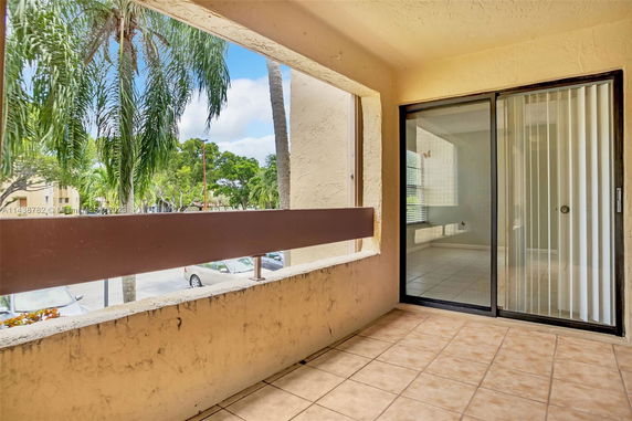 Balcony area with a view of trees and a parking lot.
