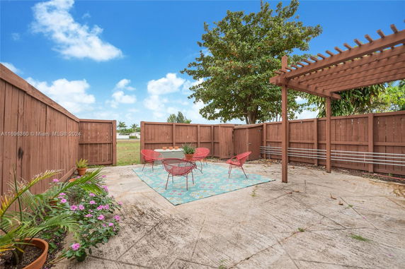 Outdoor patio area with wooden fencing, seating, and a pergola.