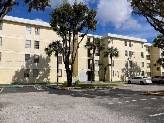 Front view of a multi-story building with parking area.