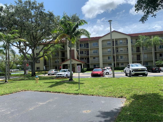 Front view of a multi-story apartment building with balconies and parking area.