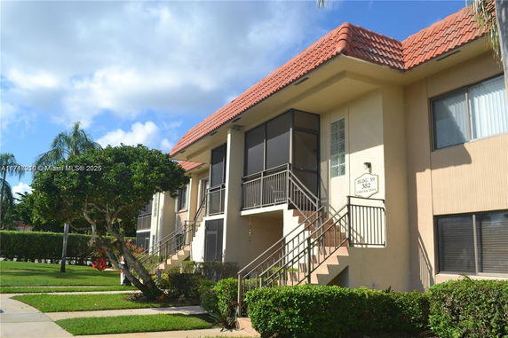 Front view of a two-story building with outdoor staircases and a red tiled roof.