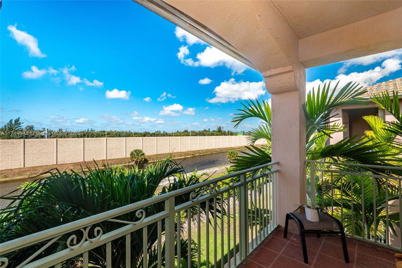 View from a balcony overlooking a canal and a tall wall in the distance.