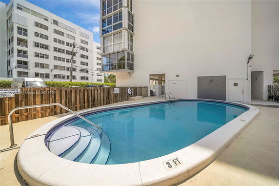 Outdoor swimming pool adjacent to a multi-story building.
