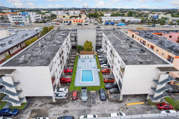 Aerial view of apartment complex with central swimming pool and parking spaces.