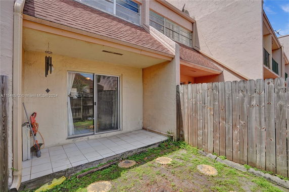 Back view of a townhouse with a fenced patio and sliding glass door.
