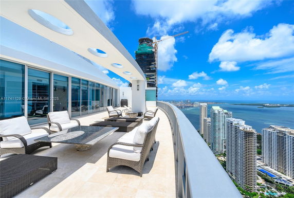 Rooftop terrace with seating area overlooking city skyline and ocean.