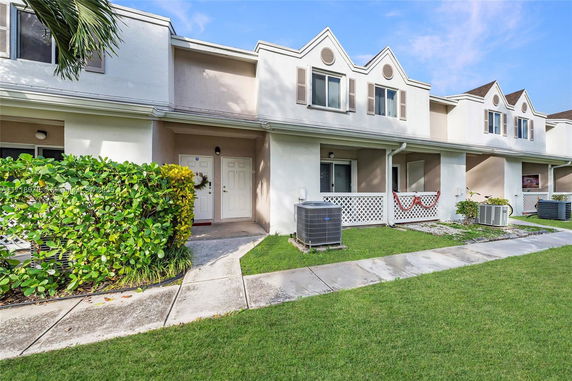 Front view of a two-story townhouse with a lawn and walkway.