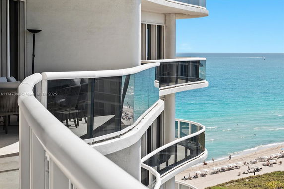 View from a building balcony overlooking a beach and ocean.