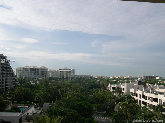 Wide view of multiple residential and commercial buildings surrounded by greenery and trees in the foreground.