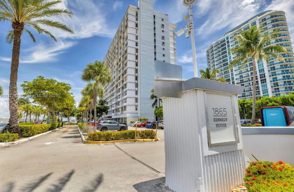 Front view of a multi-story building with palm trees lining the driveway.