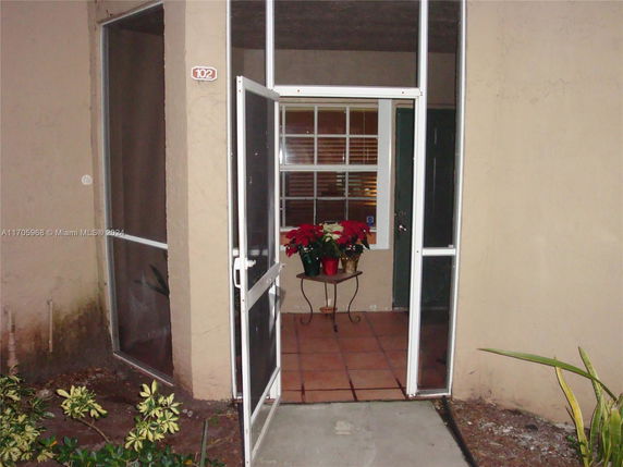 Entrance of a house with a screen door and potted plants.