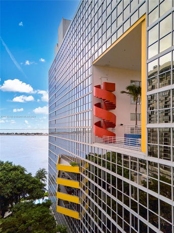 Modern high-rise building with a reflective glass facade and colorful balconies.