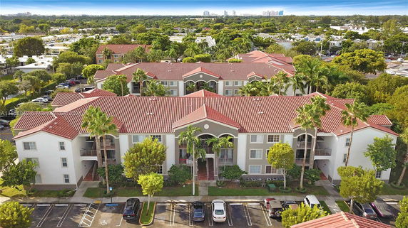 Aerial view of a complex with multiple buildings featuring red-tiled roofs and surrounding greenery.