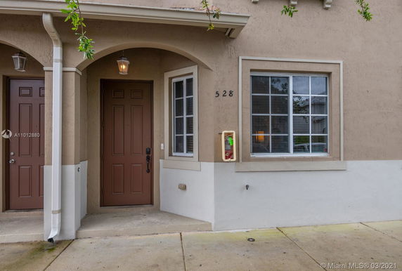 Front view of a house with an arched entryway and brown door.