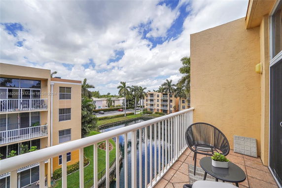 Panoramic view from a balcony showing multi-story buildings and palm trees.