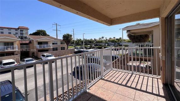 View from a balcony showing a parking area and nearby buildings.