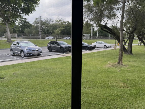Outdoor parking area with several cars parked next to a grassy area.