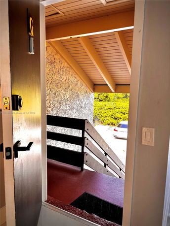 View from an open door showing an exterior staircase leading down, with a textured wall and wooden overhang.