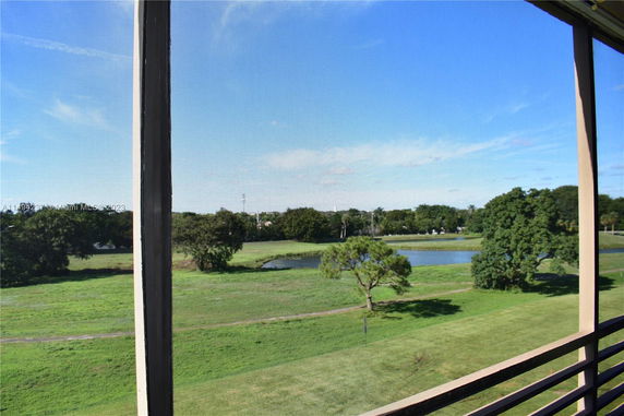 View from a building showing grassy area with trees and a small pond.