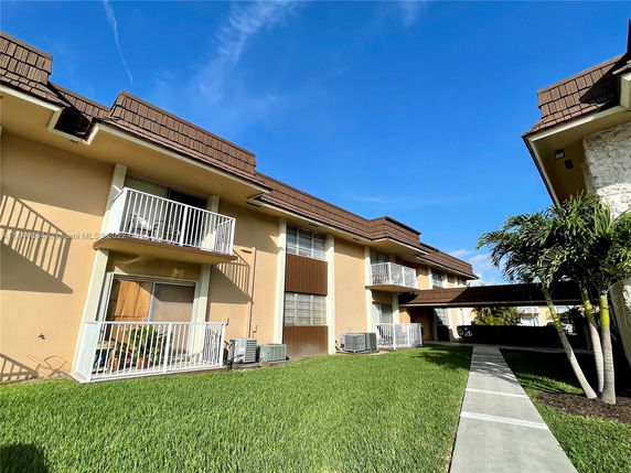 Front view of a two-story building with balconies and air conditioning units.