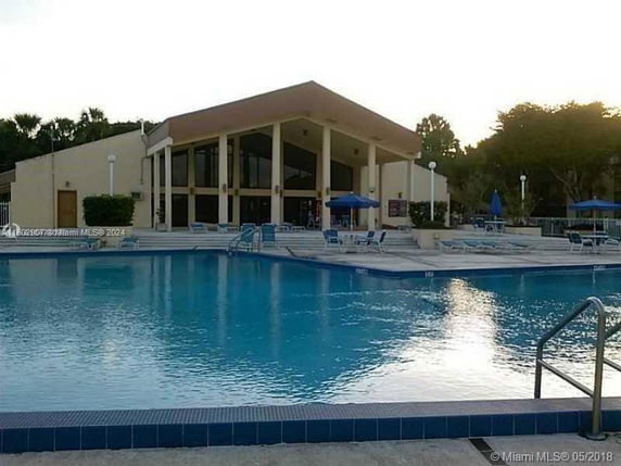 Outdoor swimming pool area in front of a modern building with large glass windows.